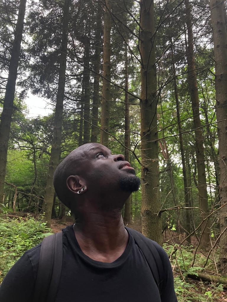 Creative's Mark founder, Geoffrey Idun, in a forest looking up at the sky.