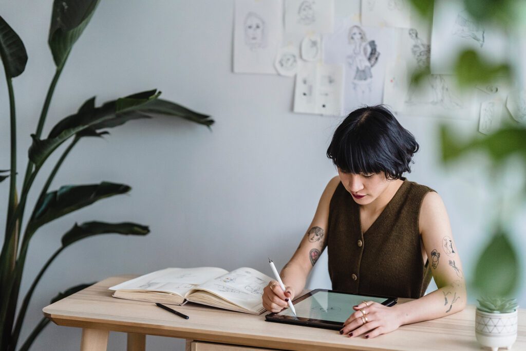 Young asian woman writing on tablet in her home office.