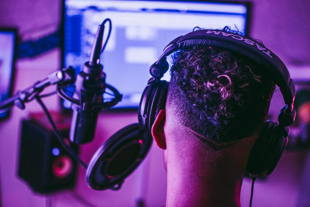 A man wearing headphones in front of a monitor in a recording studio.